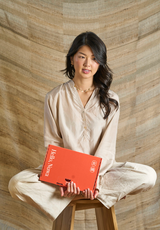 Founder Lin Loke sits cross-legged while holding a Nuwa Productivity mailer box.