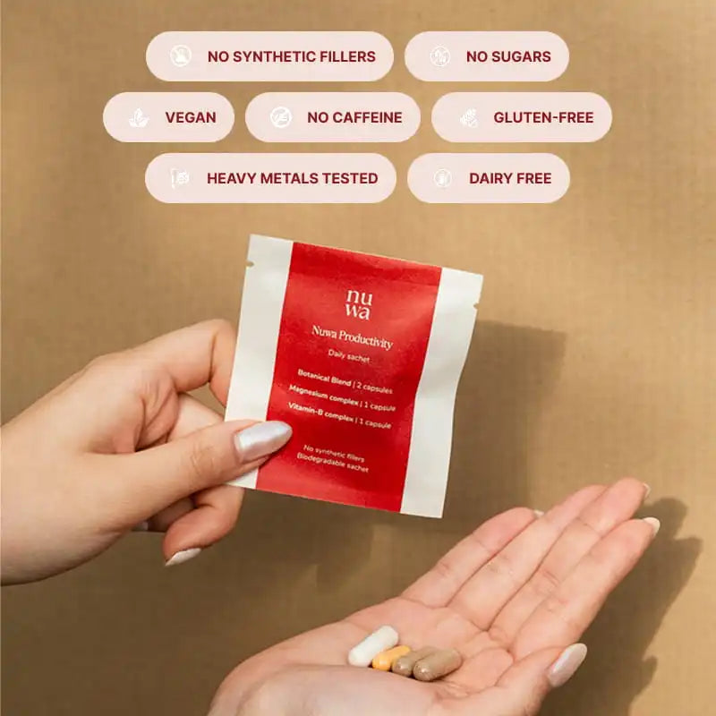 A person holds a small red-and-white Nuwa capsule packet above their open palm, which contains four capsules. The background is a warm tan textured surface with six white rounded badges listing product benefits: no synthetic fillers, no sugars, vegan, no caffeine, gluten-free, and heavy metals tested.