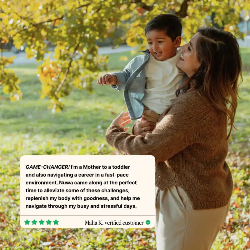 A woman in a brown knit sweater holds a smiling toddler boy outdoors in a park with autumn trees. A white review card about Nuwa Daily Packs overlay appears at the lower left with a star rating and the text 'Maha K.