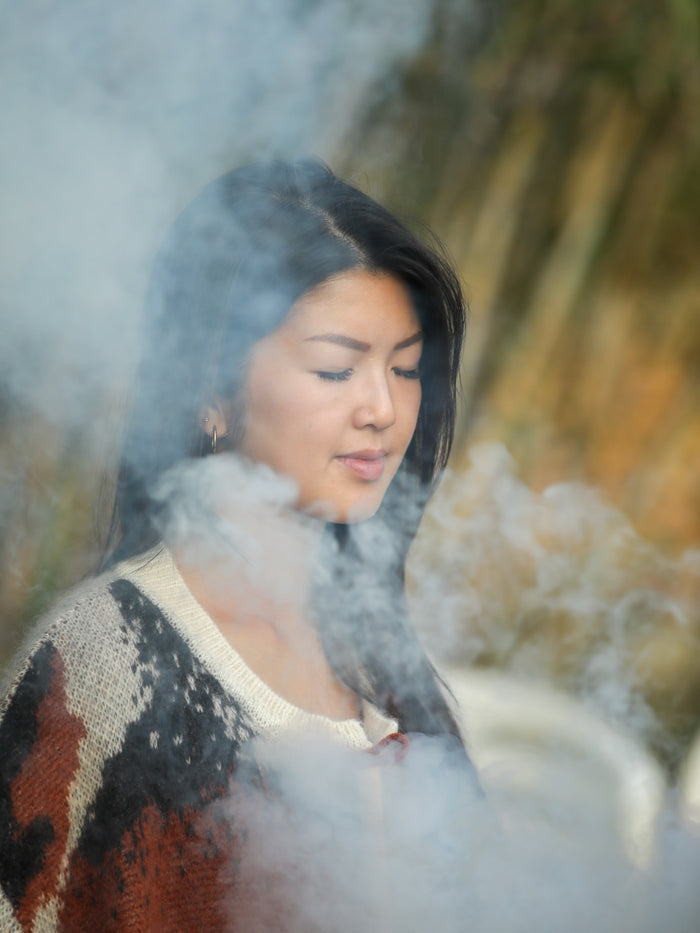 Lin with eyes closed surrounded by smoke during a wellness ceremony