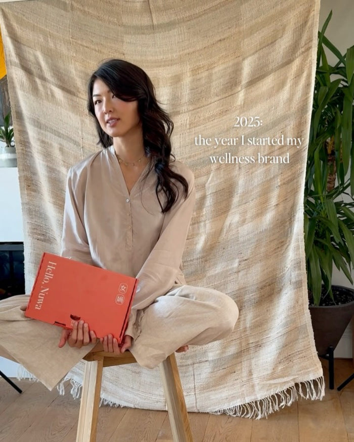 Lin sitting cross-legged holding an orange box of Nuwa daily packs